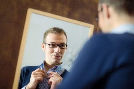Guy fixing tie in mirror for first date